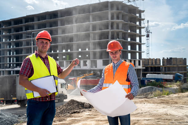 istock two young workers in uniform on construction site stand with plan and compare with the new building 1352256268