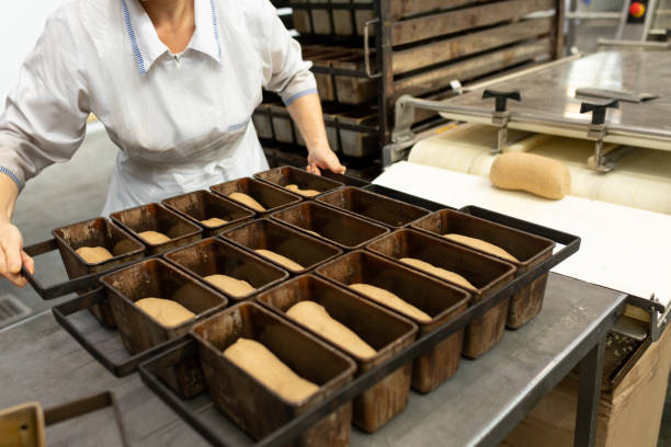 istock Baker fills baking dish with dough. Bread production stage in small bakery 1352257081