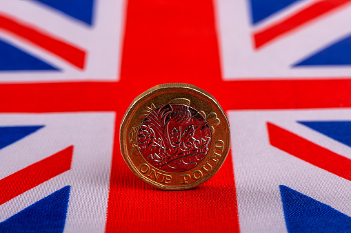 One pound coin against the background of a fragment of the flag of Great Britain