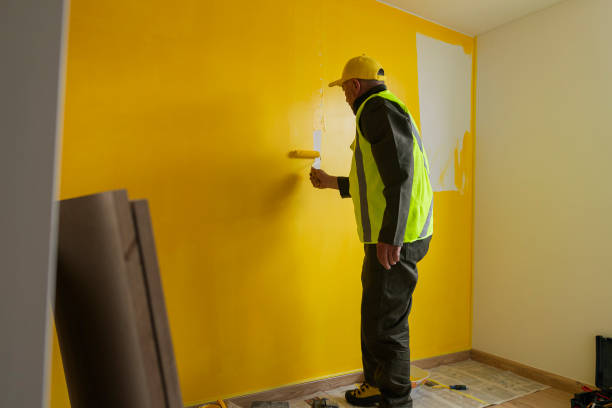 worker paints the house yellow to hand it over to the new owners - house painter paint roller yellow painting imagens e fotografias de stock