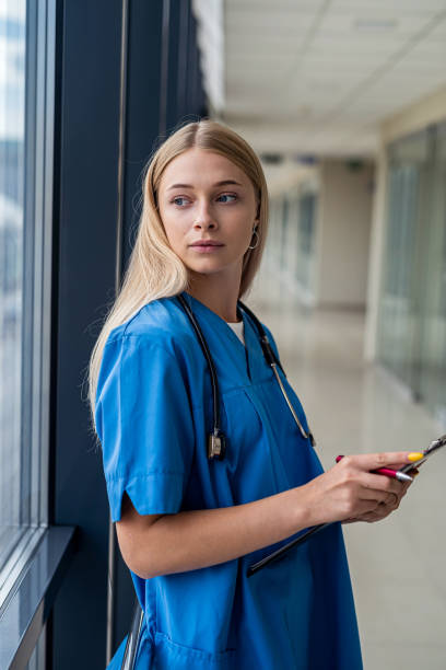 istock beautiful young nurse standing in  hallway with a tablet 1352259253