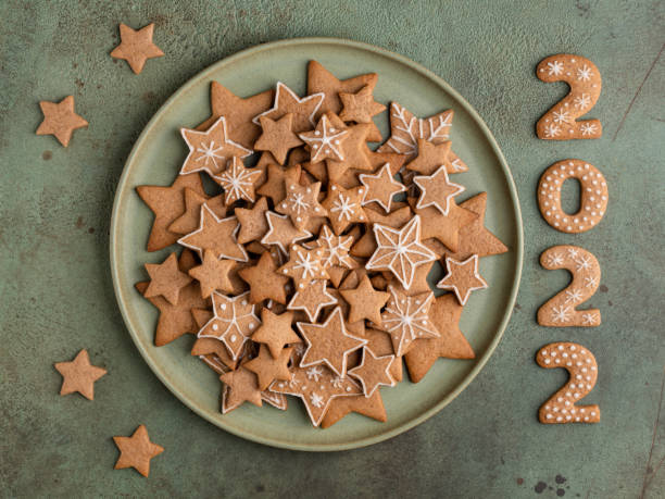 gingerbread cookies with icing on green ceramic plate. star shaped and 2022 numbers biscuits. christmas cooking background. - cookie christmas shortbread food imagens e fotografias de stock