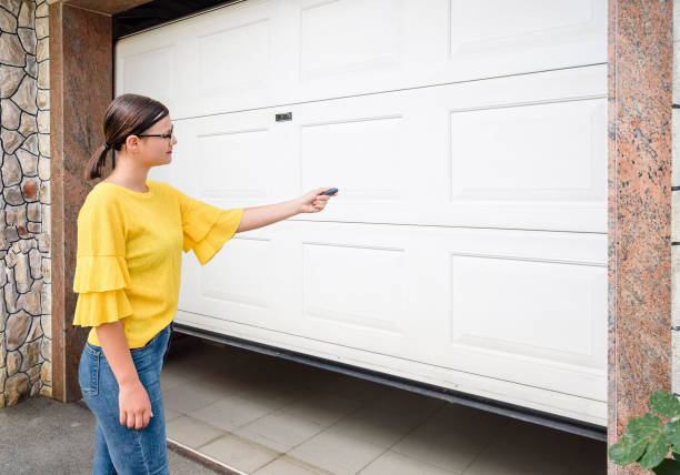 女の子や若い女性は、ガレージのドアを閉め、開くためのリモートコントローラを保持しています - house residential district residential structure car ストックフォトと画像