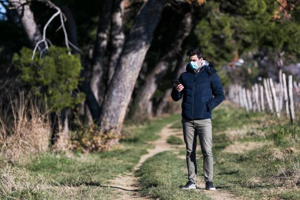 istock Man with surgical mask protecting himself from corona virus talking on mobile 1352262378