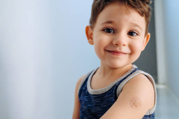 Boy showing bandaged arm after getting vaccine