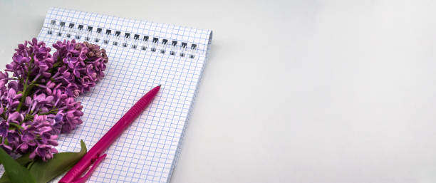 istock Spiral notebook and pen. Notepad with pen and flowers. Notebook lilacs on white background. 1352262915