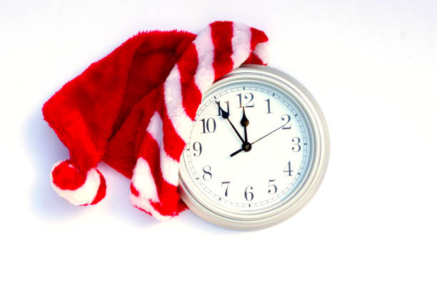silver clock showing five minutes to 12 with Christmas Santa hat on