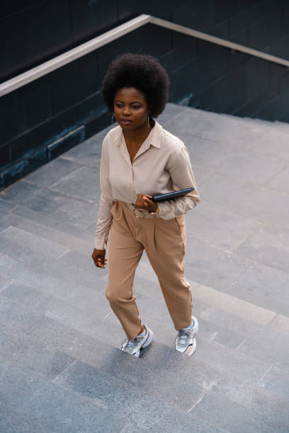 istock A high angle view on a young dark skinned woman in a beige classical outfit going up the stairs 1352264928