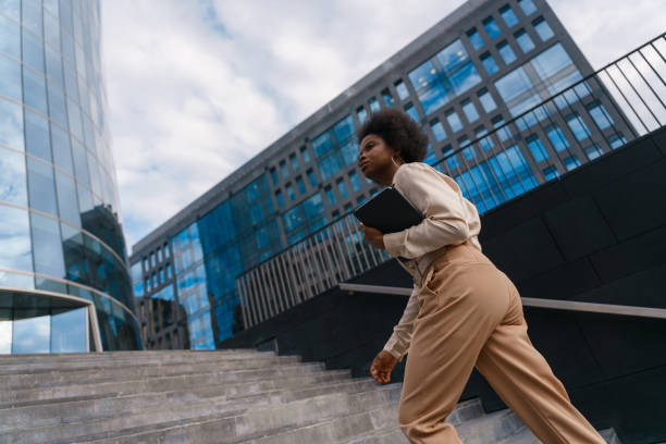 istock View from the low angle on a dark skinned business lady in a summer classical outfit ascending the stairs 1352265166