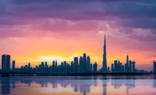 Stunning panoramic view of the Dubai skyline during a beautiful sunset with a silky smooth water flowing in the foreground. Dubai, United Arab Emirates. stock photo