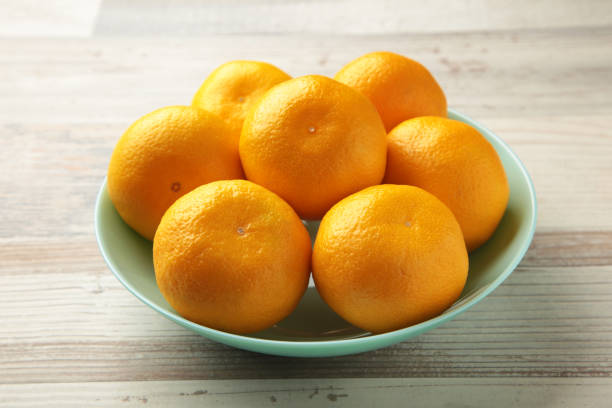 istock Fresh mandarin oranges fruit on mint bowl on grey wooden background. 1352267652