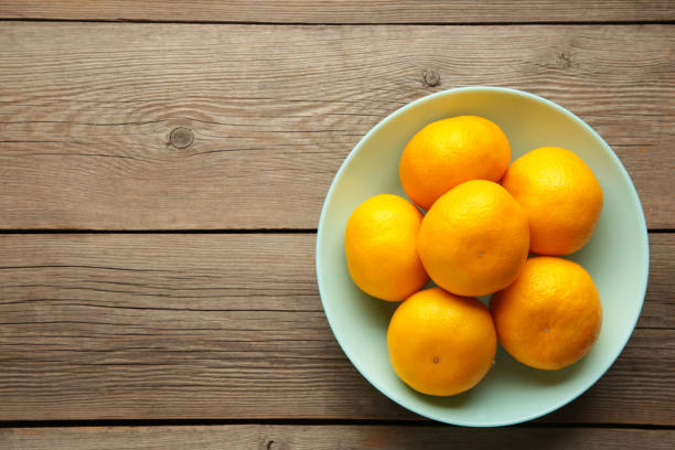 istock Fresh mandarin oranges fruit on mint bowl on wooden background. 1352267715