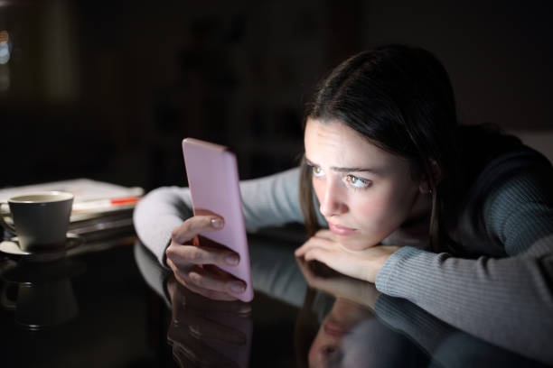 Worried woman checking smart phone in the dark night stock photo