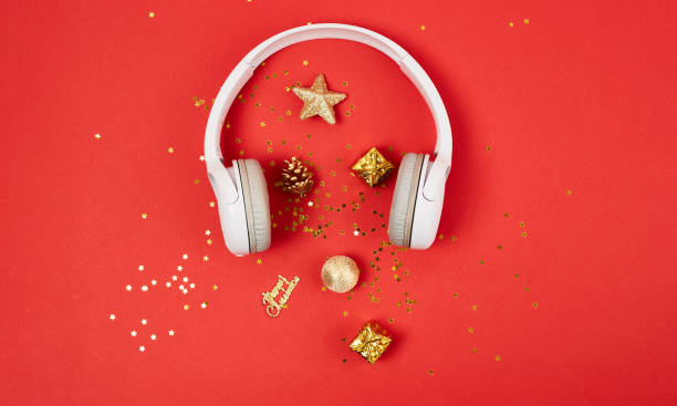 クリスマス音楽やポッドキャストの背景。赤い背景に黄金のクリスマスの装飾と白いヘッドフォン。クリスマスの新年またはパーティーのバナー - home  audio ストックフォトと画像