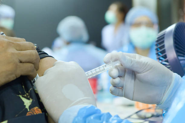 close-up and selective focus of doctor hand who is vaccinating on upper arm of people - immune defence fotos imagens e fotografias de stock