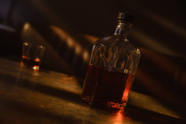 istock Alcohol in a transparent bottle refracts the rays of warm sunset light in an empty room. 1352273158