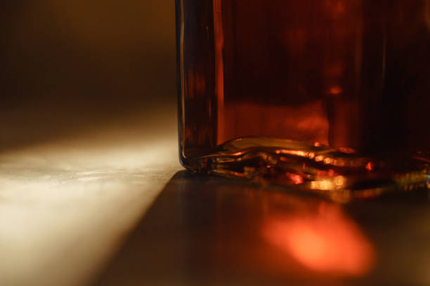 close-up de uma garrafa de vidro de uísque. iluminado por uma luz de contorno. - cognac bottle - fotografias e filmes do acervo