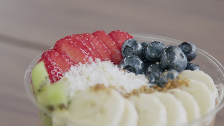 Close-Up Handheld Macro Shot of a Healthy Acai Food Bowl on a Wooden Table Outdoors in the Summer