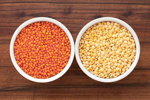 Top view of two bowls side by side with red and yellow lentils