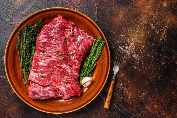 raw beef skirt meat steak on a rustic plate with herbs. dark background. top view. copy space - circular skirt fotos imagens e fotografias de stock