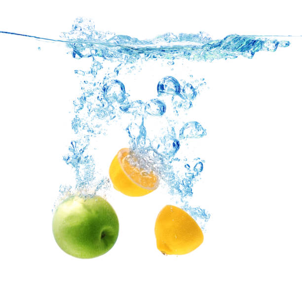 istock Apple and lemon falling down into clear water against white background 1352279225