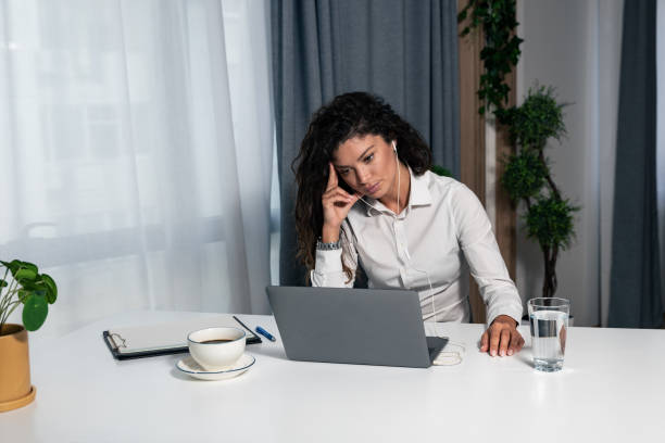 istock Focused young businesswoman working with documents in modern office sitting at work desk with laptop, serious employee checking financial report project statistics reading correspondence from clients 1352279598