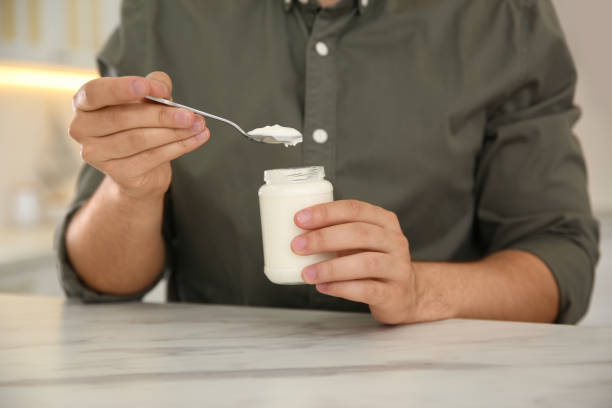 istock Young man with tasty yogurt at white marble table, closeup 1352280533