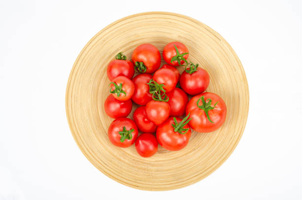 istock large wooden bamboo dish with ripe tomatoes. Studio Photo. 1352281084