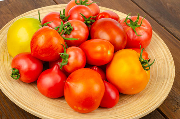 istock large wooden bamboo dish with ripe tomatoes. Studio Photo. 1352281094