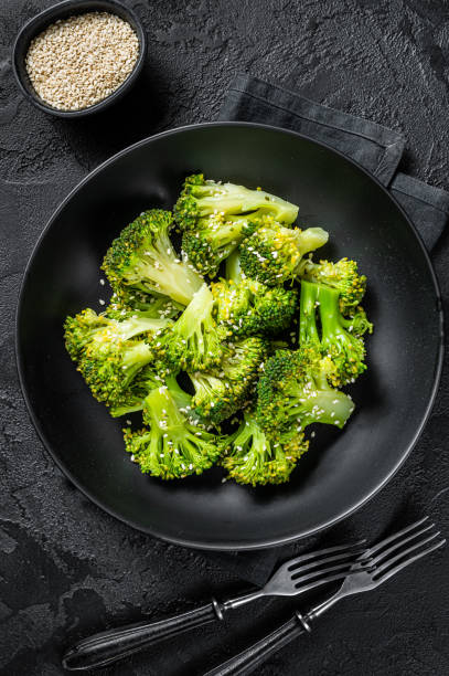 istock Boiled broccoli with spices in a plate. Black background. Top view 1352282885