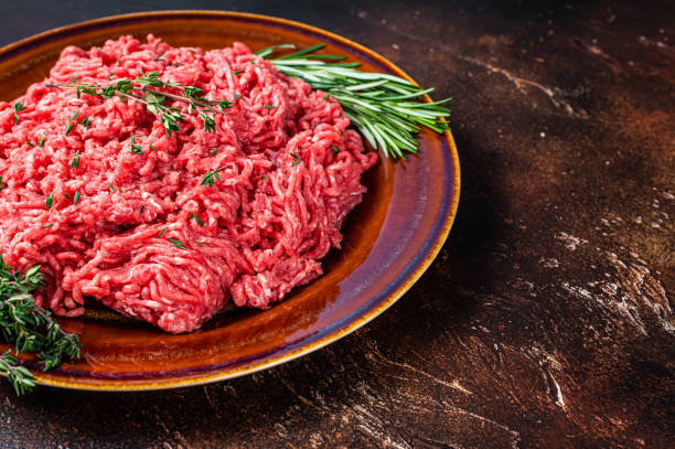 istock Raw mince beef and lamb meat on a rustic plate with herbs. Dark background. Top view. Copy space 1352283652
