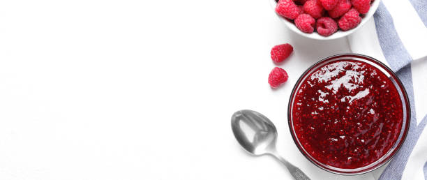 istock Delicious jam and fresh raspberries on white table, flat lay. Space for text 1352284345