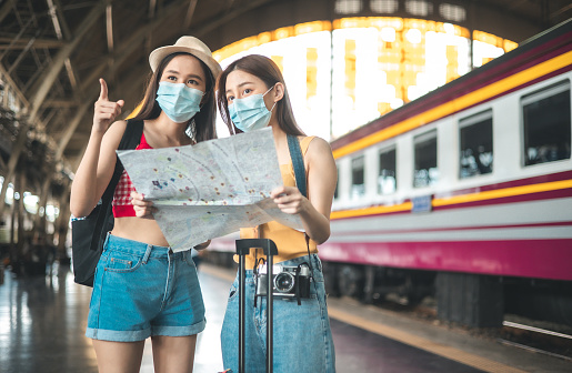 Asian woman with a mask walking on the platform and waits for an electric train.Portrait of young  woman with antiviral  mask on her face . public transport is moving metro train.