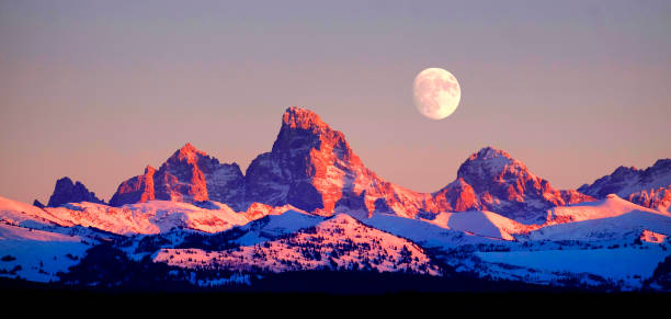 Sunset light with alpen glow on Tetons Tetons mountains rugged with moon rising Sunset light with alpen glow on Tetons Tetons mountains rugged with moon rising idaho photos stock pictures, royalty-free photos & images