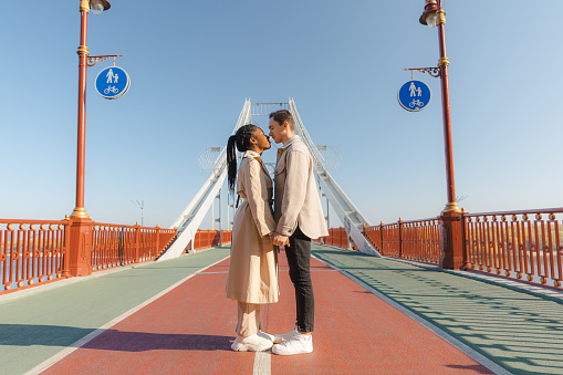 Heterosexual couple, black woman and Caucasian man, standing on the bridge and looking at scenic view of Dnipro river