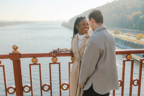 чернокожая женщина и кавказец стоят на мосту - couple autumn embracing bridge стоковые фото и изображения