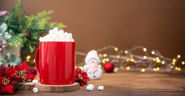 Red mug with hot chocolate and marshmallows with Christmas decoration on background, bokeh lights and copy space