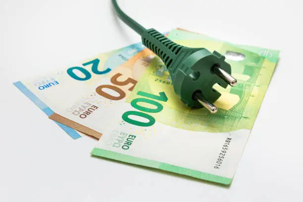 Green plug on euro banknotes - on white background Renewable energy and finance concept