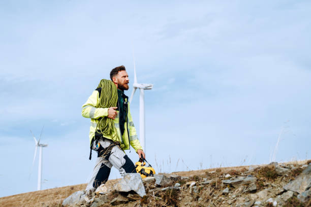 istock Wind turbine technician walking on field path towards wind turbines with climbing equipment 1352294429