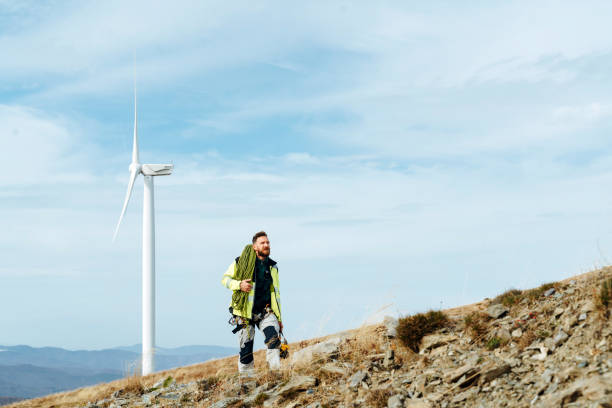 istock Wind turbine technician walking on field path towards wind turbines with climbing equipment 1352294432