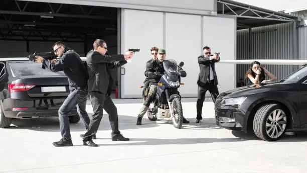 Tactical exercise training. An armed bodyguard security team protects a celebrity vip person in danger combat situation when attacked. Security police team in civilian black suit with sunglasses