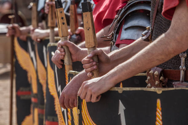 Roman legionaries in formation. Hands holding pila, javelin Roman legionaries in formation. Hands holding pila or javelins. Faint eagle-wing and thunderbolt motifs on the scuta roman centurion stock pictures, royalty-free photos & images