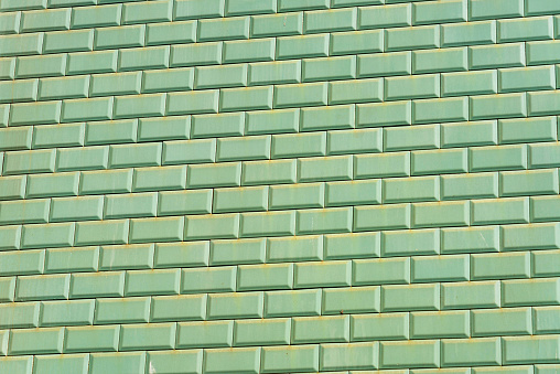 An exterior wall of plain green tiles.