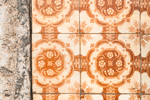 Macro image showing the intricate patterns of traditional brown tiles on the exterior of a large apartment building in Lisbon, Portugal.