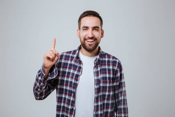 istock Smiling Bearded man in shirt pointing up 1352297524