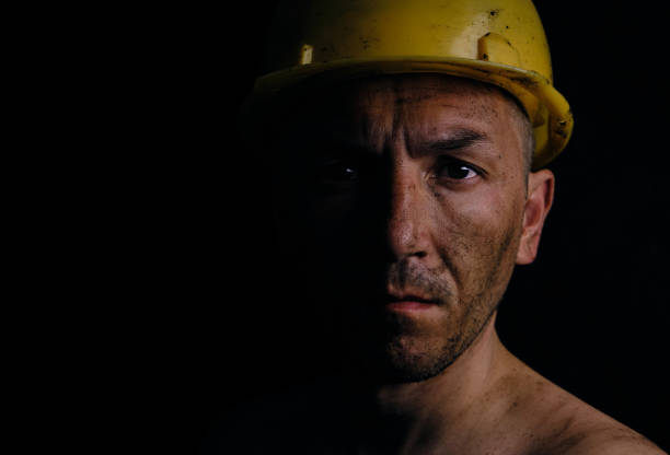 mineur dans un casque de sécurité jaune sur fond noir sale de poussière de charbon. - mid adult men portrait hat human face photos et images de collection