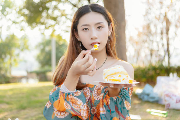 istock An Asian beauty eats cake at an outdoor picnic. 1352297950