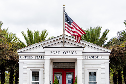 Seaside, USA - January 9, 2021: Town in Florida panhandle with Post Office sign in city town beach gulf of mexico, white architecture new urbanism and American flag