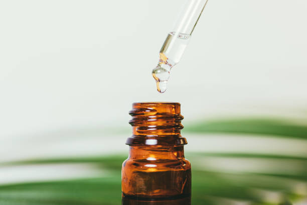 istock Organic essential oil drop drips into amber glass bottle 1352299086