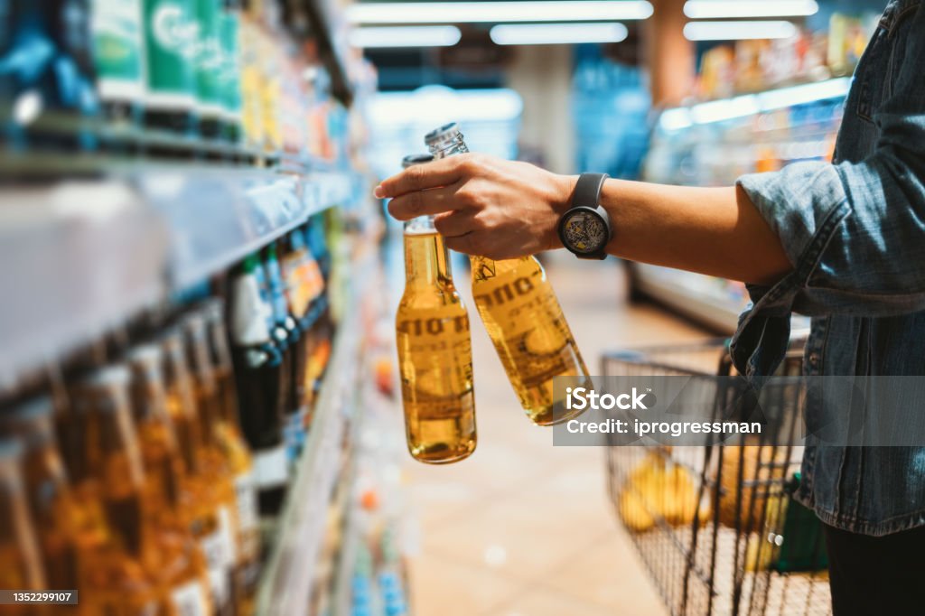 Close-up of female hand holding two glass bottle Close-up of female hand holding two glass bottle with alcoholic drink in store Alcohol - Drink Stock Photo